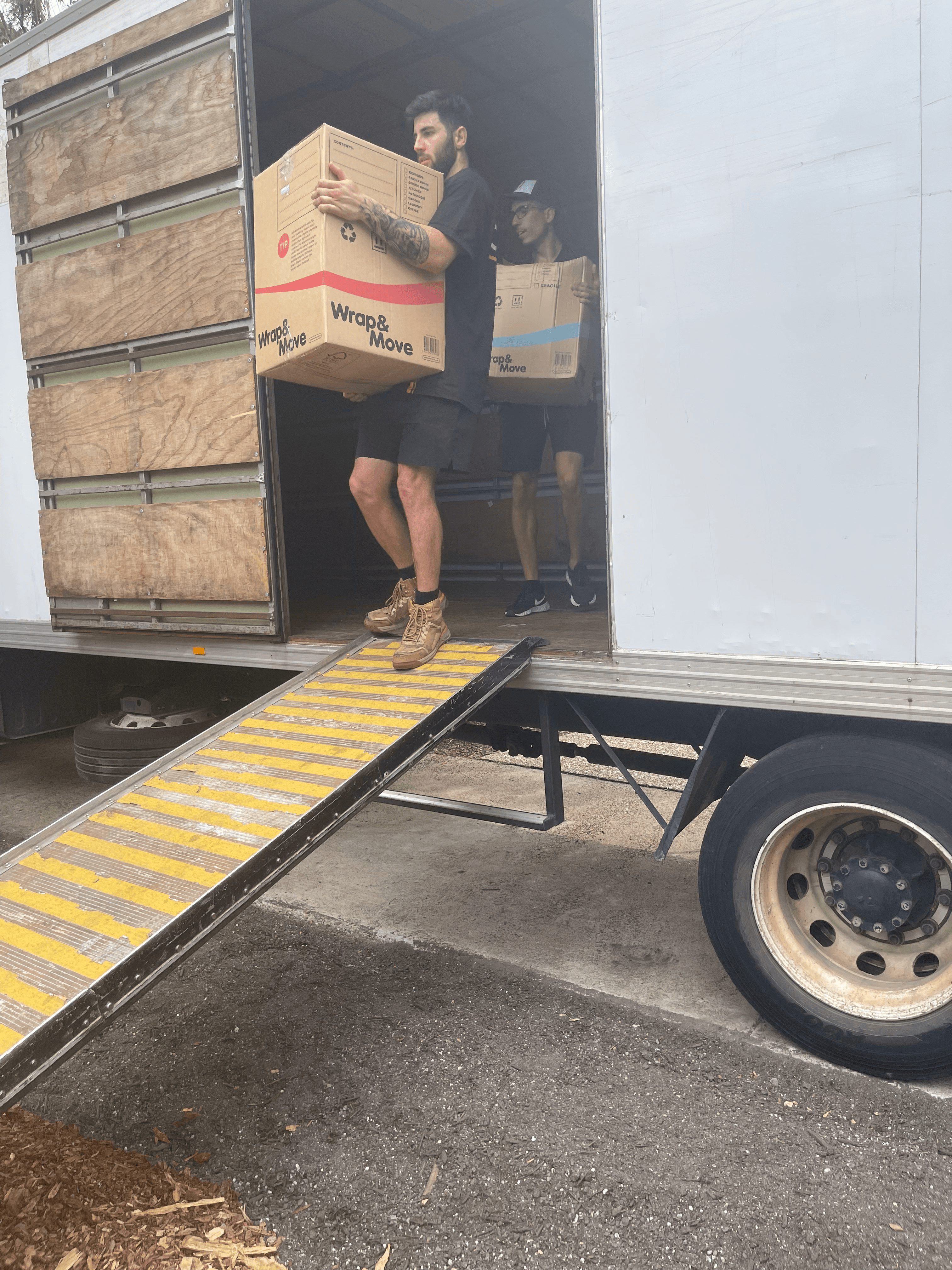 Mover in an Oz Wide Movers singlet loading office furniture onto a tail lift