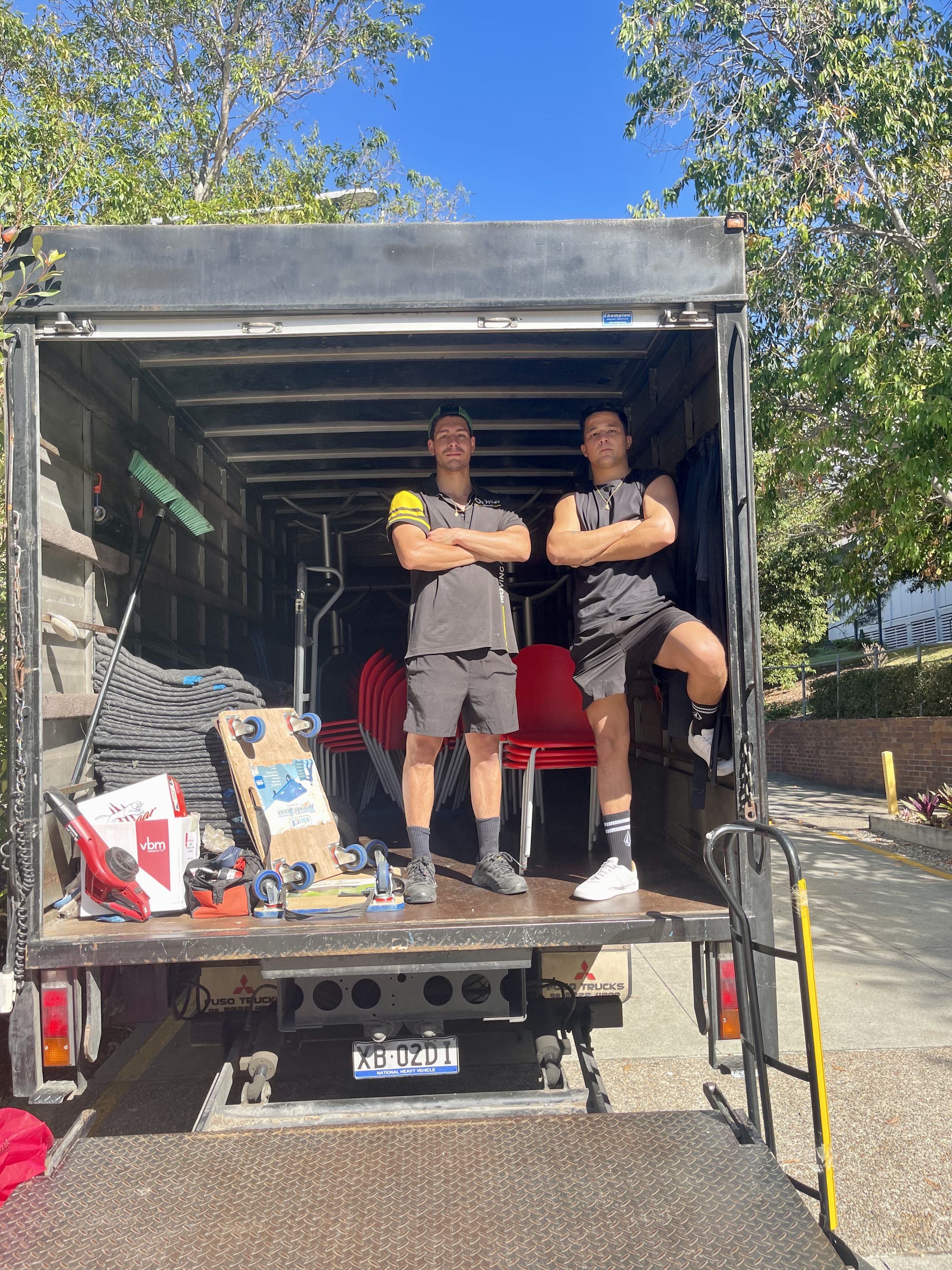 Four movers carrying an oversized soft toy down the truck ramp